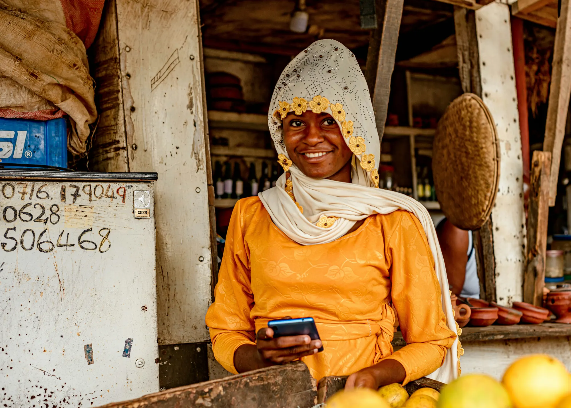 Commerçante souriante tenant son téléphone devant son étal